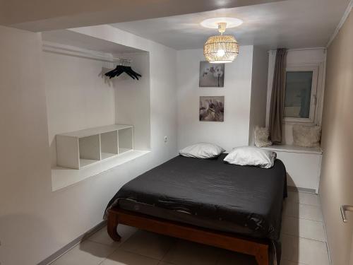 a bedroom with a black bed in a white room at L'appart de juju in Petite Île