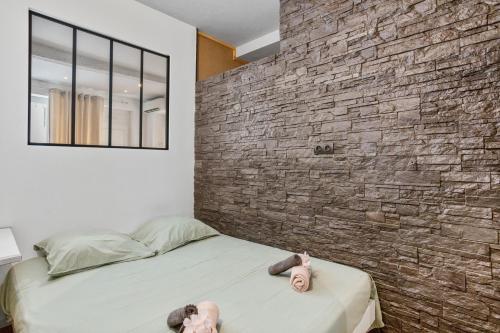two dolls sitting on a bed in a room with a brick wall at Le Loft 11 Draguignan in Draguignan