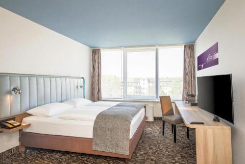 a hotel room with a bed and a desk and a television at Best Western Plus Hotel Dresden City in Dresden