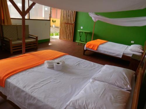 2 camas en una habitación con paredes verdes en Tambopata Hostel, en Puerto Maldonado