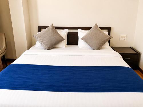 a large bed with blue and white sheets and pillows at Hotel Maurya Regency in Morjim