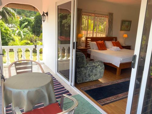 a bedroom with a bed and a table and a chair at The Orchard Holiday Home in Mahe