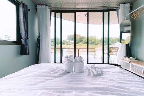 a pair of white shoes sitting on a bed with a window at แพ River Tale Uthaithani in Ban Khok Mo