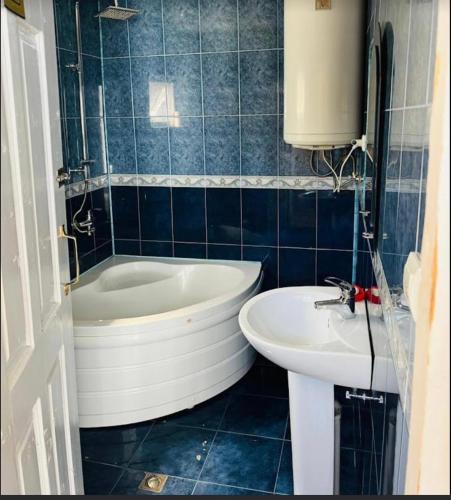 a blue tiled bathroom with a tub and a sink at Family hotel ucha in Iprari