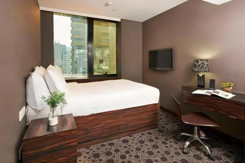 a hotel room with a bed and a desk and a television at J Link Hotel in Hong Kong