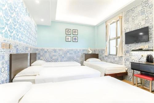 a room with four beds and a flat screen tv at Hou Kong Hotel in Macau