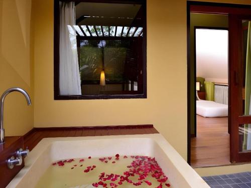 a bathroom with a bath tub filled with pink flowers at Baan Talay Dao Resort in Hua Hin