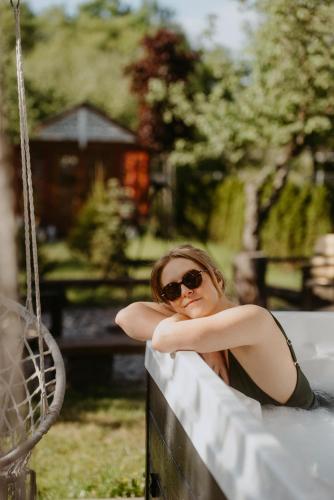 a woman in sunglasses sitting on a swing at STACJA RUDA in Złota Wieś