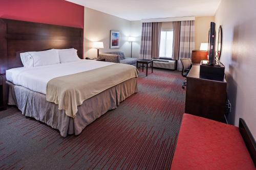 a hotel room with a large bed and a living room at Holiday Inn Express Hotel and Suites Duncan, an IHG Hotel in Duncan