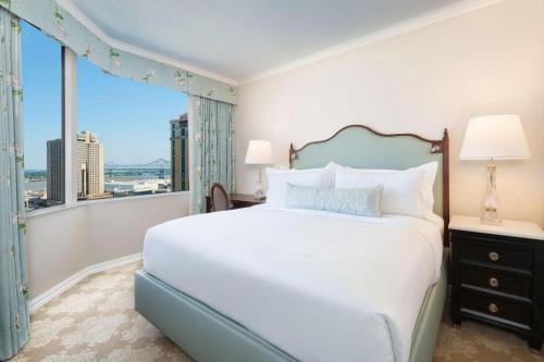 a bedroom with a large bed and a large window at The Windsor Court in New Orleans