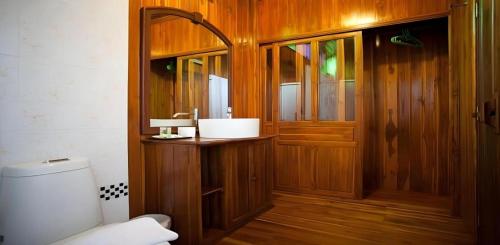 a bathroom with a toilet and a wooden door at Srisawat Resort in Cha Am