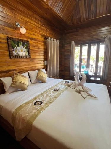 a large bed in a room with wooden walls at Srisawat Resort in Cha Am