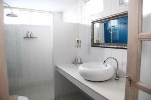 a white bathroom with a sink and a mirror at Baan Hmon-Oon in Chiang Mai