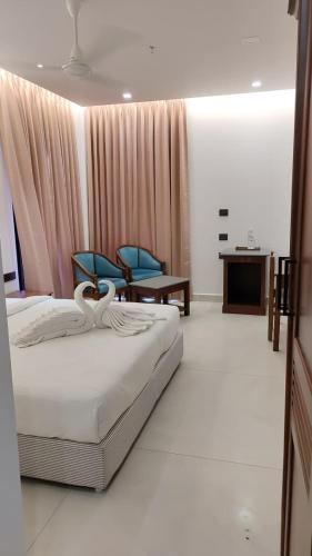 a bedroom with a bed and two blue chairs at Hotel Elite International in Trichūr