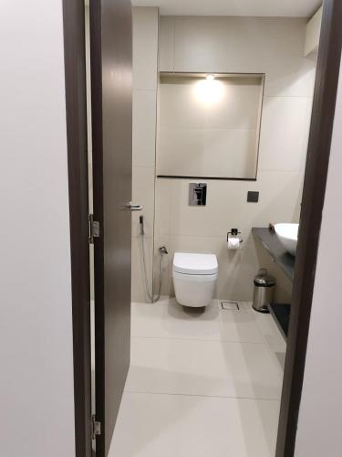 a white bathroom with a toilet and a sink at Hotel Elite International in Trichūr