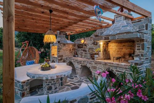 an outdoor patio with a stone fireplace and a table at Amaranthos Garden Retreat in Skopelos Town