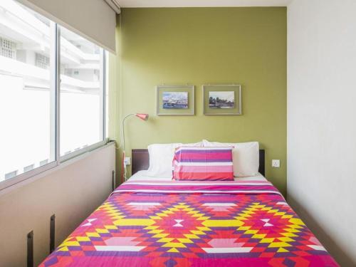 a bedroom with a bed with a colorful blanket on it at G4 Station Backpackers Hostel in Singapore