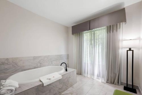 a white bathroom with a tub and a window at Comfort Suites New Bern near Cherry Point in New Bern