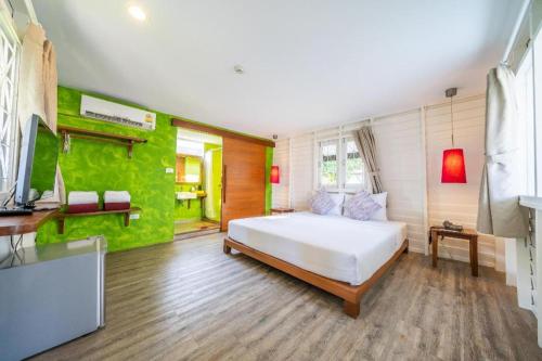 a bedroom with a white bed and a green wall at Baan Supparod in Ko Samed