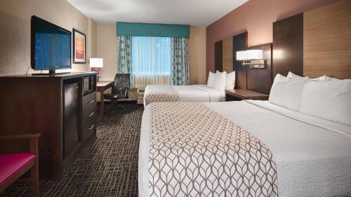 a hotel room with two beds and a flat screen tv at Best Western Fort Myers Inn and Suites in Fort Myers