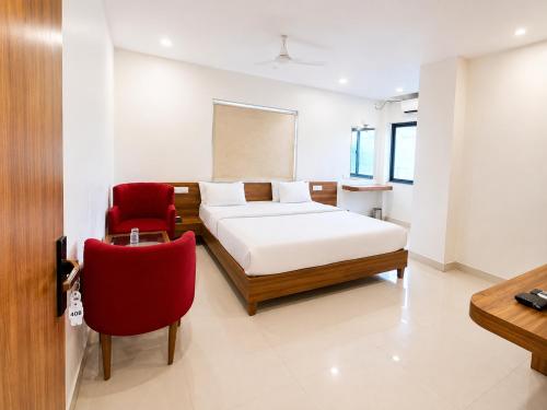 a bedroom with a bed and a red chair at Hotel The Amrit in Jabalpur
