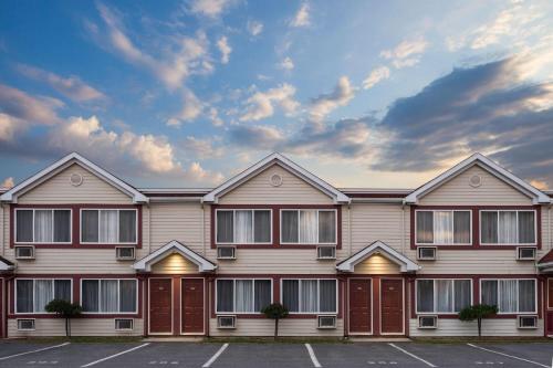a building with red doors in a parking lot at Travelodge by Wyndham Drummondville in Drummondville