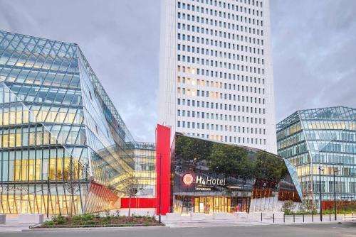 a large glass building with a sign in front of it at H4 Wyndham Paris Pleyel in Saint-Denis