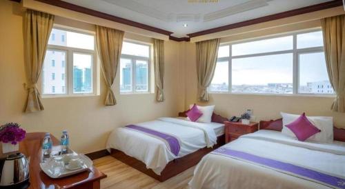 a hotel room with two beds and two windows at The Mou Hotel in Phnom Penh