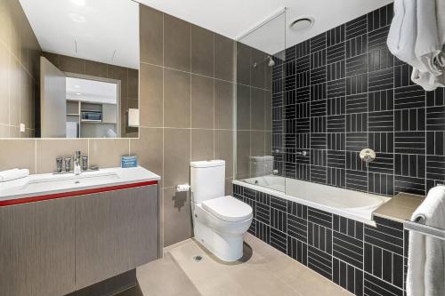 a bathroom with a toilet and a sink and a tub at MainStay Suites Abbotsford in Melbourne