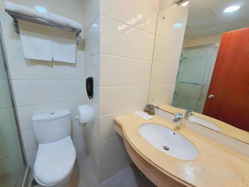 a bathroom with a toilet and a sink and a mirror at Grand Harbour Hotel in Macau