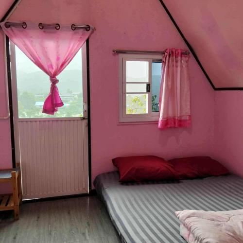 a bedroom with pink walls and a bed with a window at กลางขุนเขา klang khun khao in Ban Na Yang
