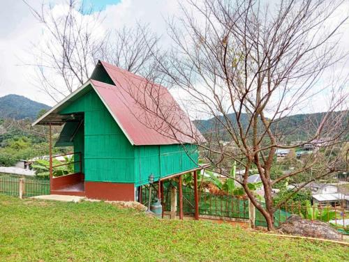 a green and red building on a hill with a tree at กลางขุนเขา klang khun khao in Ban Na Yang