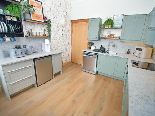 a kitchen with blue cabinets and a wooden floor at The Beltie Flat in Newton Stewart