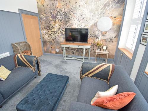 a living room with two blue couches and a tv at The Beltie Flat in Newton Stewart
