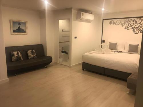 a bedroom with a bed and a couch and a mirror at white house in Phangnga