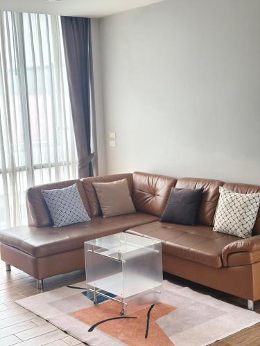 a living room with a brown couch and a glass coffee table at โรงแรม เดอะโมเดล การ์เด้น in Yasothon