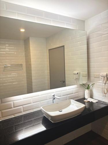 a bathroom with a sink and a large mirror at โรงแรม เดอะโมเดล การ์เด้น in Yasothon