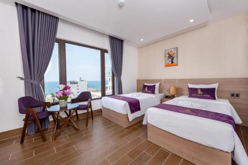 a hotel room with two beds and a table at Maison Hotel Phu Quoc in Phú Quốc