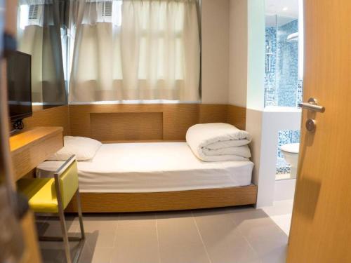 a small bedroom with a bed and a window at Acesite Knutsford Hotel in Hong Kong