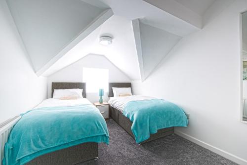 two beds in a room with white walls at Crosshills Serviced Apartments in Leeds