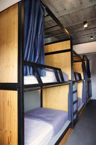 two bunk beds in a room with blue curtains at Poonpun Pet Friends Poshtel in Chanthaburi