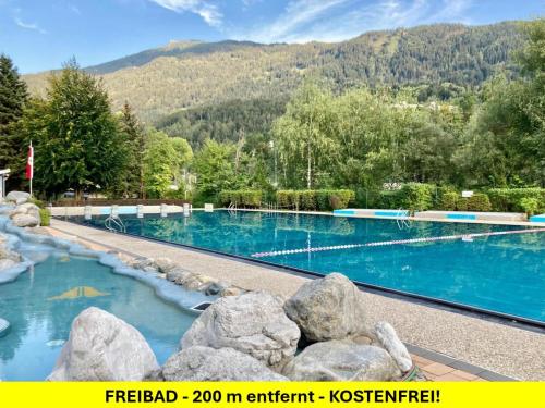 a swimming pool with blue water and mountains in the background at Hotel Enzian in Landeck