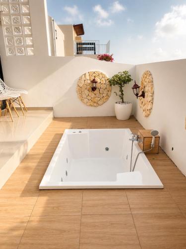 a white bath tub in a room with a wooden floor at Villa With Jacuzzi, Damar Ningrum 3 in Tutugan