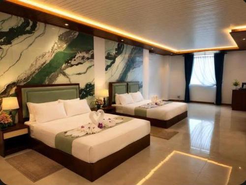 a room with two beds and a painting on the wall at Bravon Sky Hotel in Kurunegala