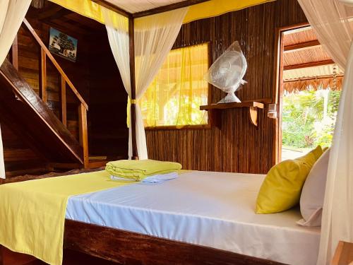 a bedroom with a bed with yellow sheets and a window at Mahanoro Hotel & Restaurant in Sainte Marie