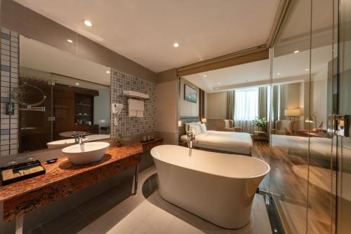a bathroom with a tub and a sink and a bedroom at Van Phat Riverside Hotel in Can Tho