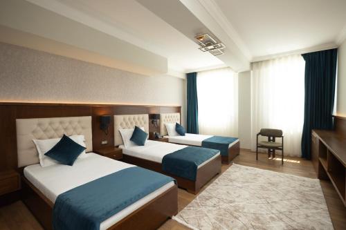 a hotel room with two beds and a desk at Alegria Hotel in Prizren