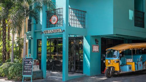 a bus parked in front of a blue building at Quba by Montraj Pattaya, previously The Quba Hotel Pattaya in Pattaya