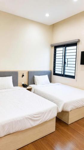 two beds in a room with a window at New Star Hotel Tay Ninh in Tây Ninh