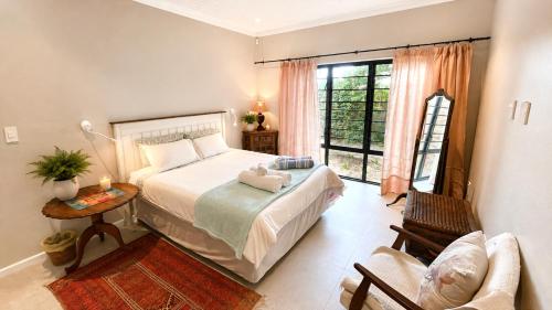 a bedroom with a bed and a table and a window at Sandy Toes Home in Plettenberg Bay